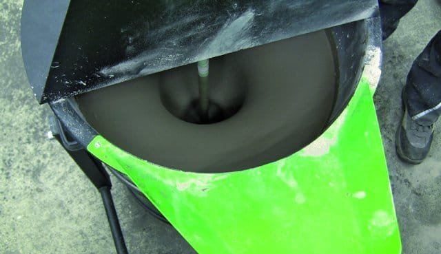 Mixing leveller process A close-up view of a mixing drum with a dark, paste-like substance being mixed inside. The drum has a green lid and is mounted on a stand.