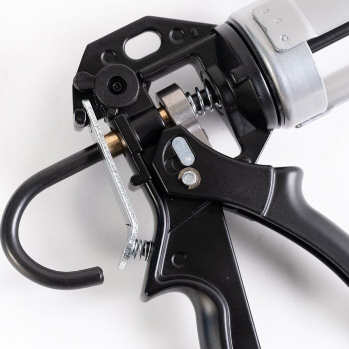 Hardtouch Duo 1 A black and silver gun resting on a flat surface, surrounded by metalware items.