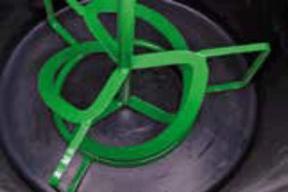 Floormix2300 station A green metal device with several loops and rods placed inside a black circular container.